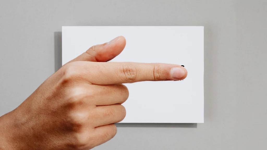 Visitenkarte auf Tisch mit dem Artur Visuals Logo. Das Logo wird von einem Finger verdeckt.
